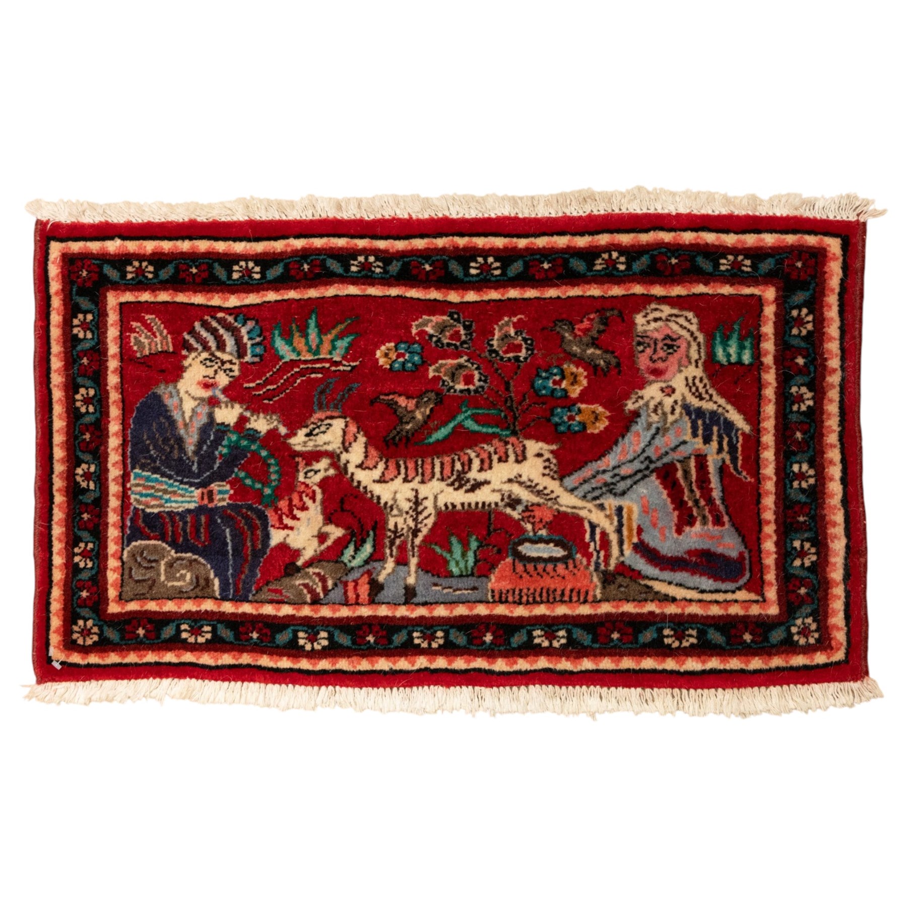 Two small rugs, an ivory ground example decorated with a central floral medallion and scattered rose sprays, enclosed by a navy foliate border (62cm x 101cm), and a crimson pictorial mat worked with seated figures, an animal and birds amongst flowering plants (45cm x 79cm) (2)