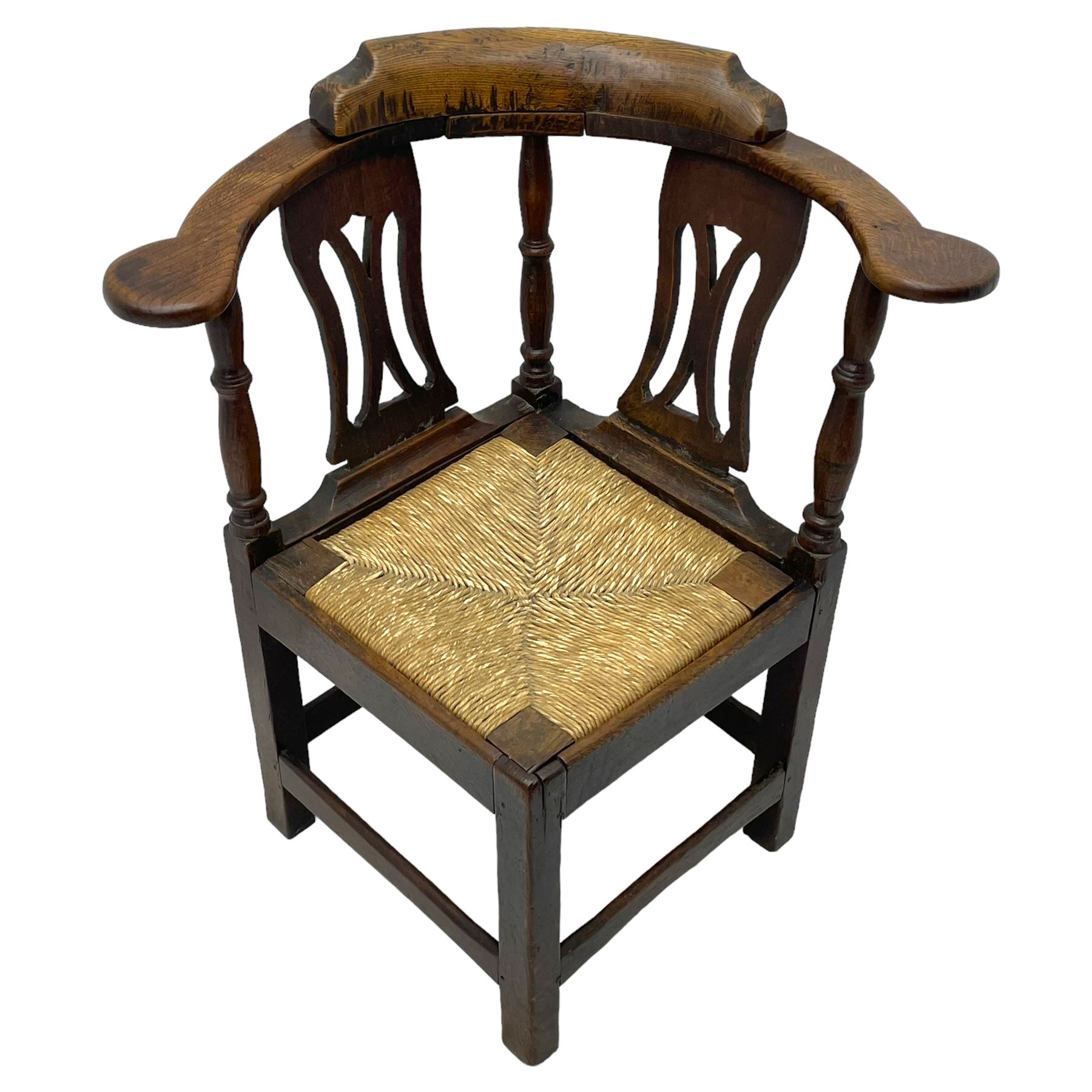 18th century country elm and oak corner chair, the shaped cresting rail terminating to swept arm resets, supported by turned columns and pierced shaped splats, over a drop-in rush seat, raised on square supports united by box stretcher
