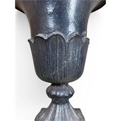 Pair of Victorian large scale cast iron garden urns, flared petal shaped rim with tapering waist, gadrooned base on square plinth, finished in black paint
