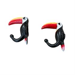 Three cast iron Guinness toucans in flight, together with two cast iron hooks