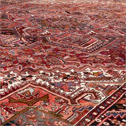 North West Persian Heriz hand-knotted carpet, brick red field, with large central angular star medallion with stepped outlines, surrounded by geometric floral devices and stylized rosettes, with corresponding corner spandrels, enclosed by a bold geometric main border with multiple guard stripes, with cotton fringe ends 