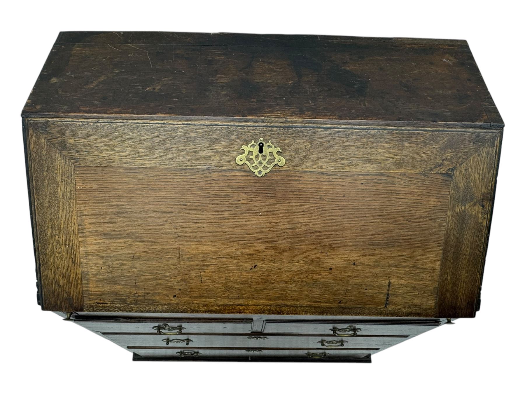 George III oak bureau, sloped fall-front enclosing a fitted interior with pigeonholes, small drawers, and a central compartment, over two short and two long drawers, brass escutcheons and drop handles, raised on bun feet