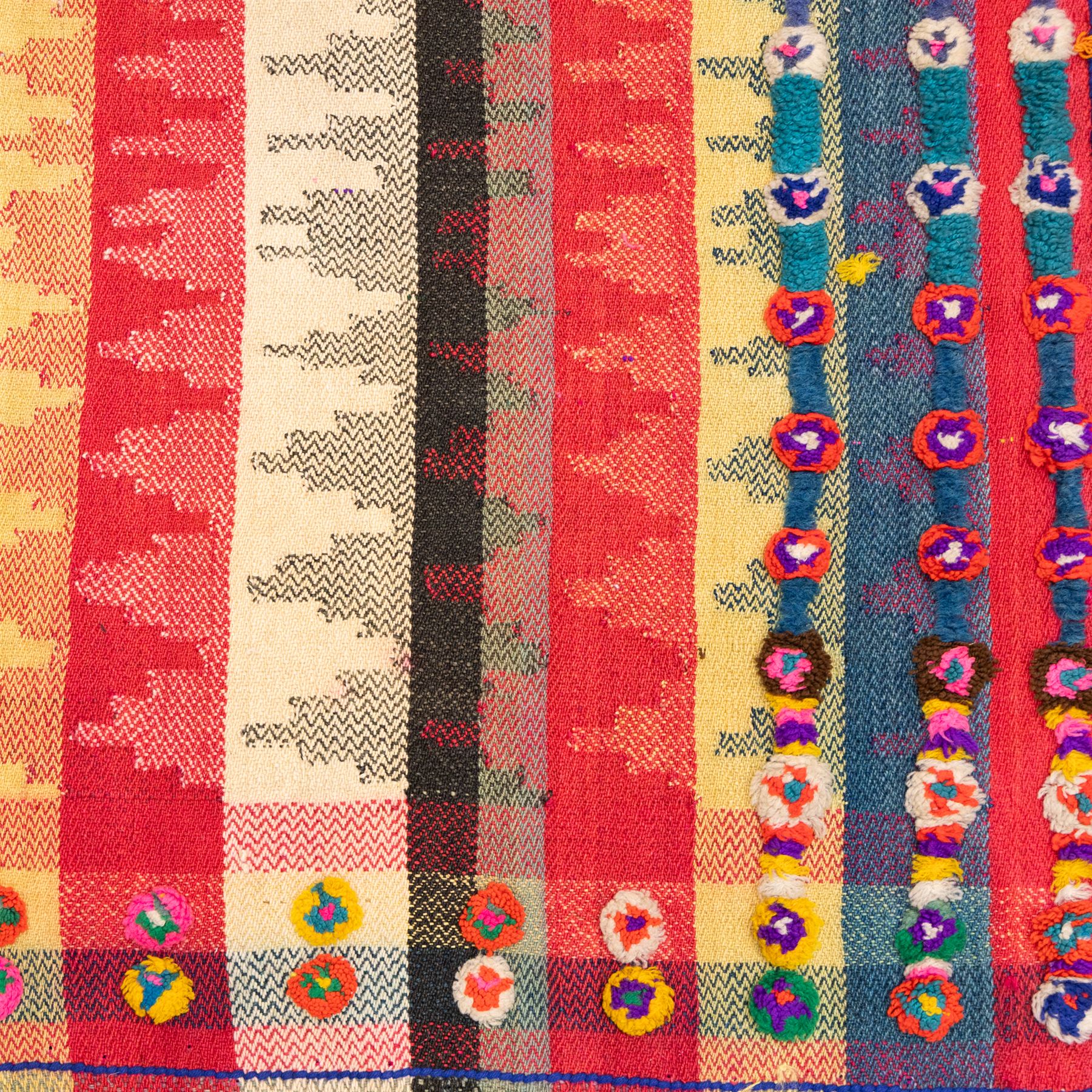 South West Persian Jajim kilim flatweave runner, woven in warp-faced flatweave and composed of narrow bands, striped field in various shades of rose, coral, ivory, indigo, turquoise, and olive, embellished along the sides with applied knotted wool rosettes and tassels, some missing (due to large size, the runner is illustrated in two sections)