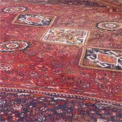 Qashqai wool carpet, red diamond-shaped field decorated with three stepped pole medallions, floral rosettes and scattered stylised motifs, within dark blue spandrels and multiple geometric guard borders