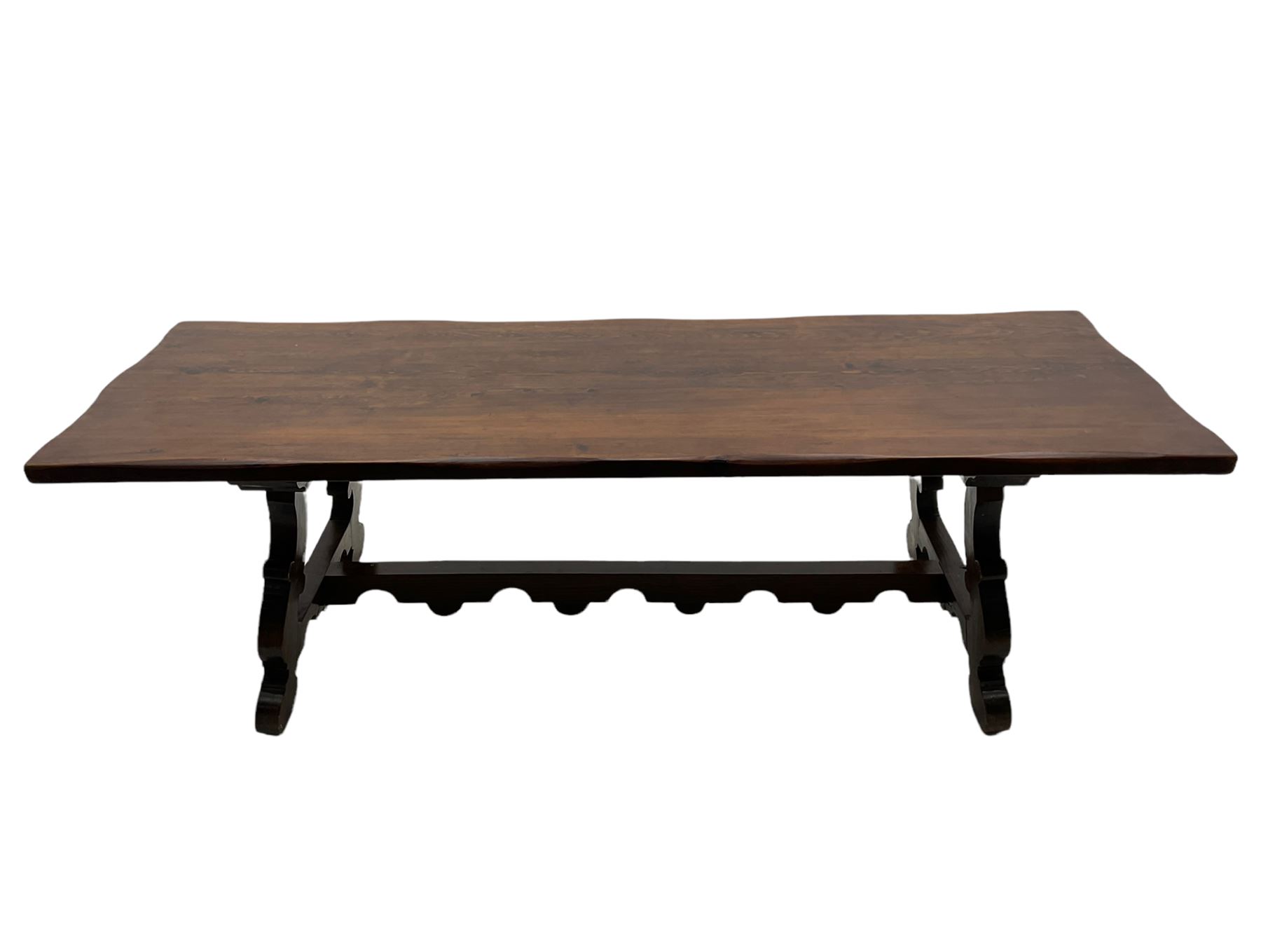 Large Spanish hardwood dining table, on shaped open ends supports joined by stretcher 
