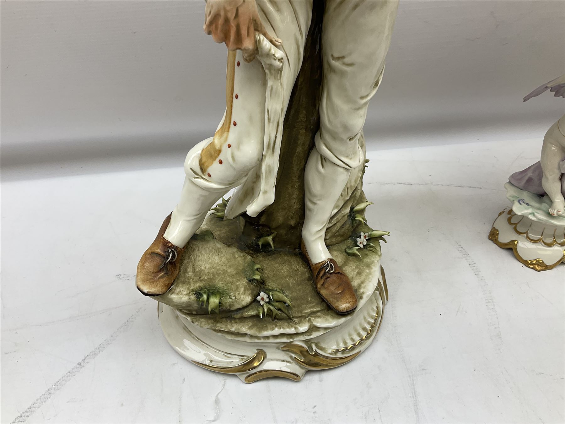 Pair of Capodimonte table lamps, in the form of cherubs holding a brass fitting, together with a pair of large Capodimonte figures in the form or a man and woman resting up on tree stump, largest example H57cm