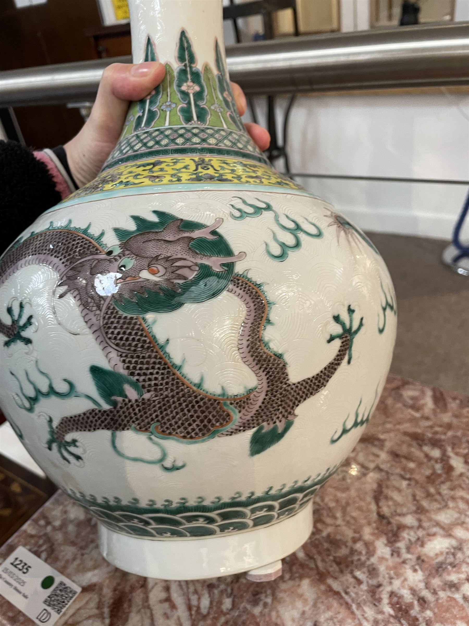 Pair 20th century Chinese famille verte bottle vases, each decorated with green and purple dragons chasing pearls amidst auspicious flames, the neck with yellow and green stylised foliate and cell borders, and the white glazed body incised throughout with fan shapes, each with red character mark beneath flanked by green dragons, H38cm

