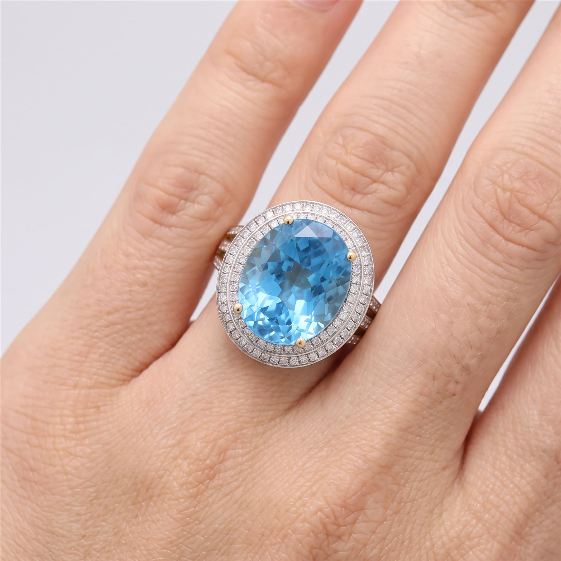14ct gold Swiss blue topaz and diamond cluster ring, single oval cut topaz of approx 8.85 carat, surrounded by two rows of single cut diamonds and split diamond set shoulders