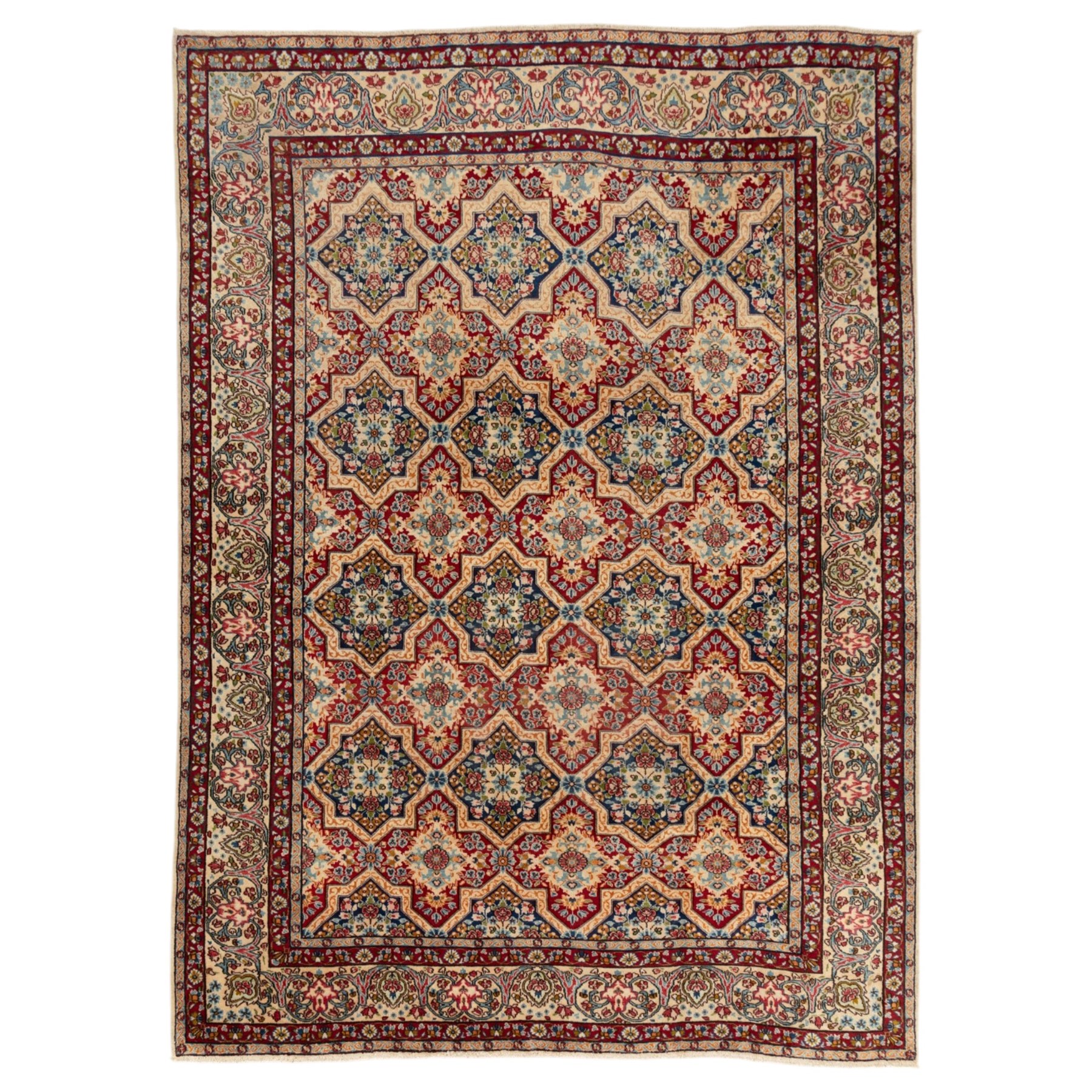 Central Persian Kirman carpet, the field arranged with alternating indigo star shaped and red cruciform compartments, each filled with rosettes, flowerheads and scrolling foliage, enclosed by a broad ivory palmette border and red floral guard bands