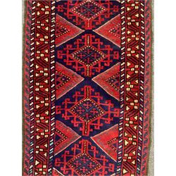 Meshwani crimson ground runner rug, the indigo field decorated with geometric lozenges, guarded border with repeating stylised shapes
