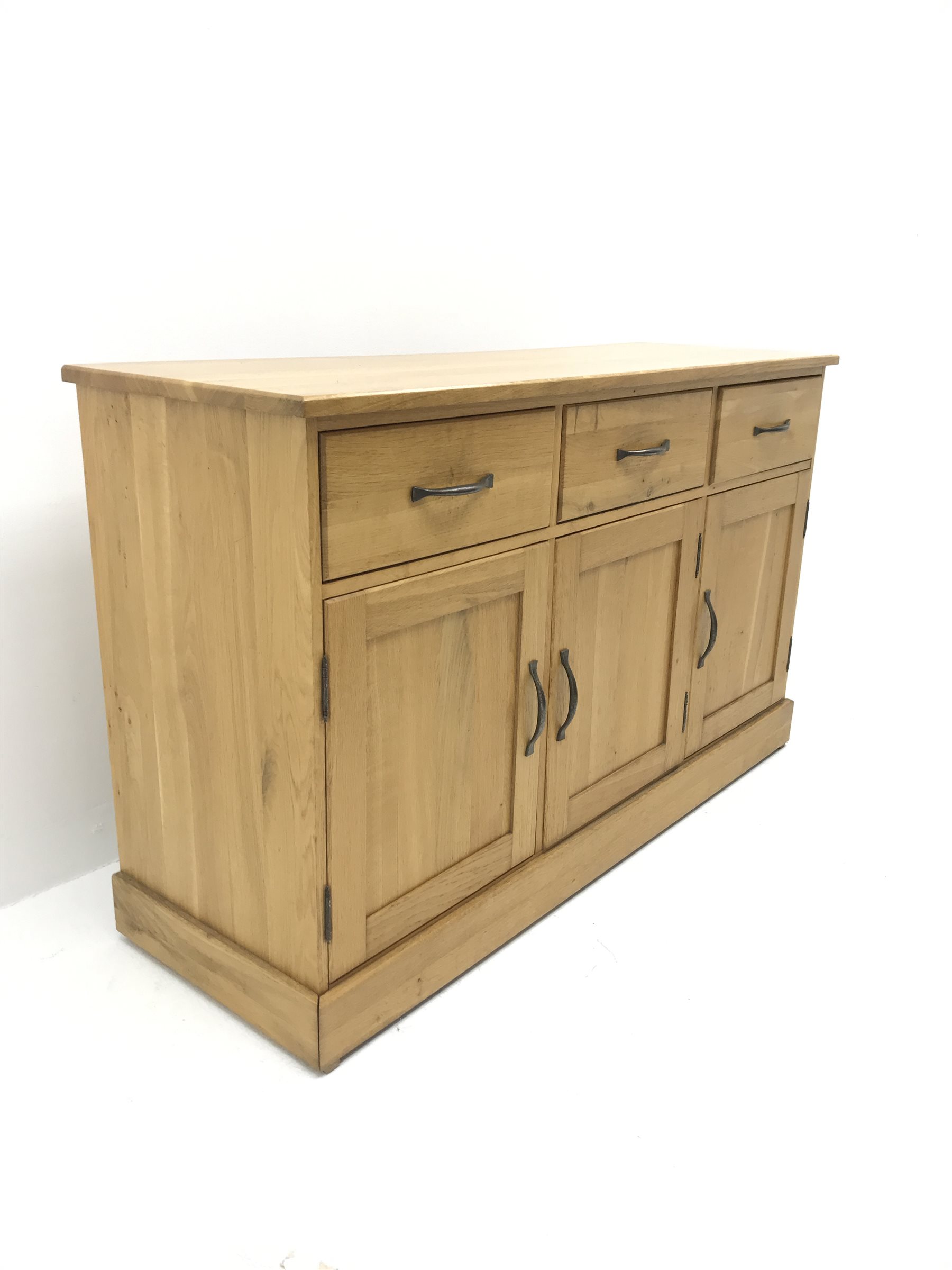Light oak sideboard, three drawers above three cupboards on plinth base
