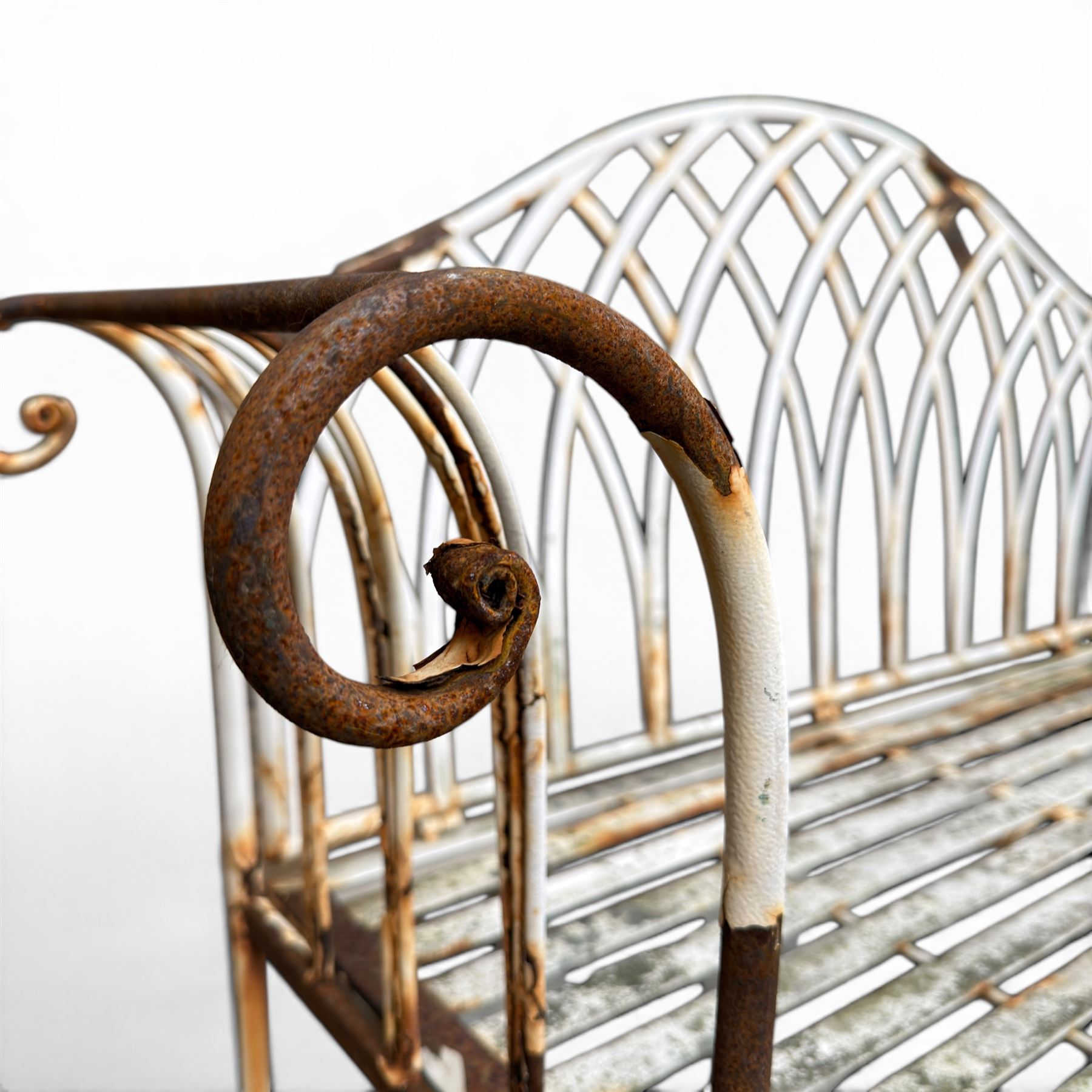 Small wrought metal two seat garden bench, finished in distressed white paint