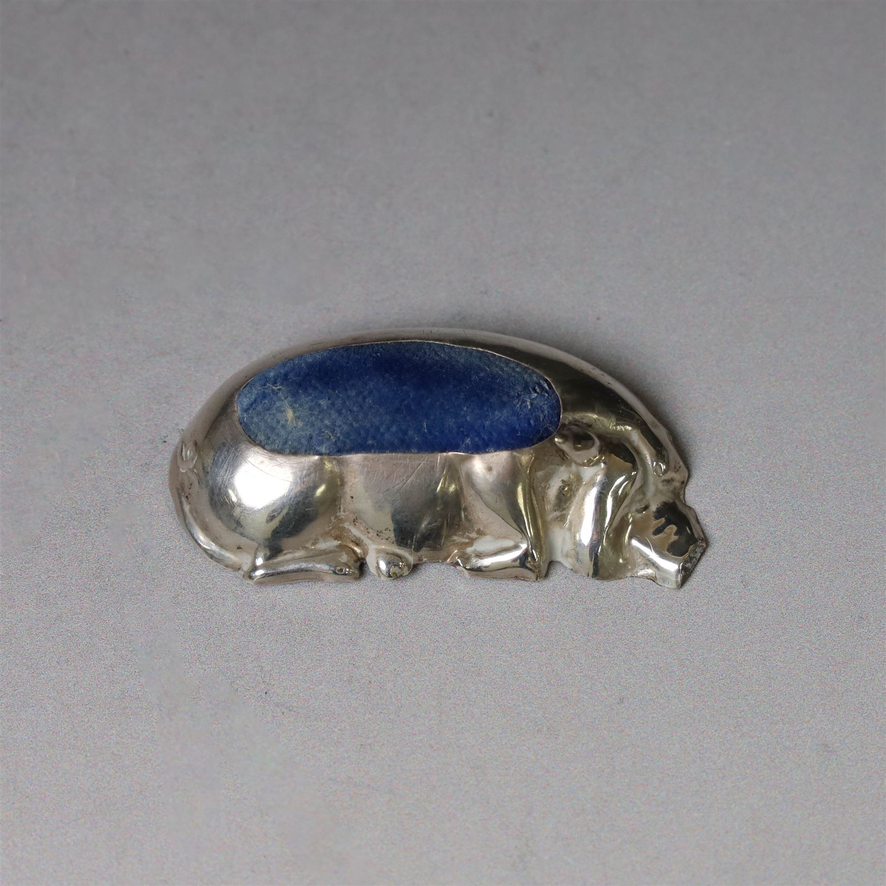 Early 20th century silver novelty pin cushion, modelled as a recumbent pig with blue cushioned back, hallmarked Williams (Birmingham) Ltd, Birmingham 1910, W5.5cm