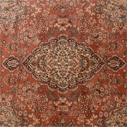 Persian vermillion ground Kashan rug, the busy field decorated with a central floral pole medallion, surrounded by trailing foliage and profusely woven floral patterns and bouquets, the dark indigo spandrels and multiple guard bands with similar floral decoration and stylised spandrels