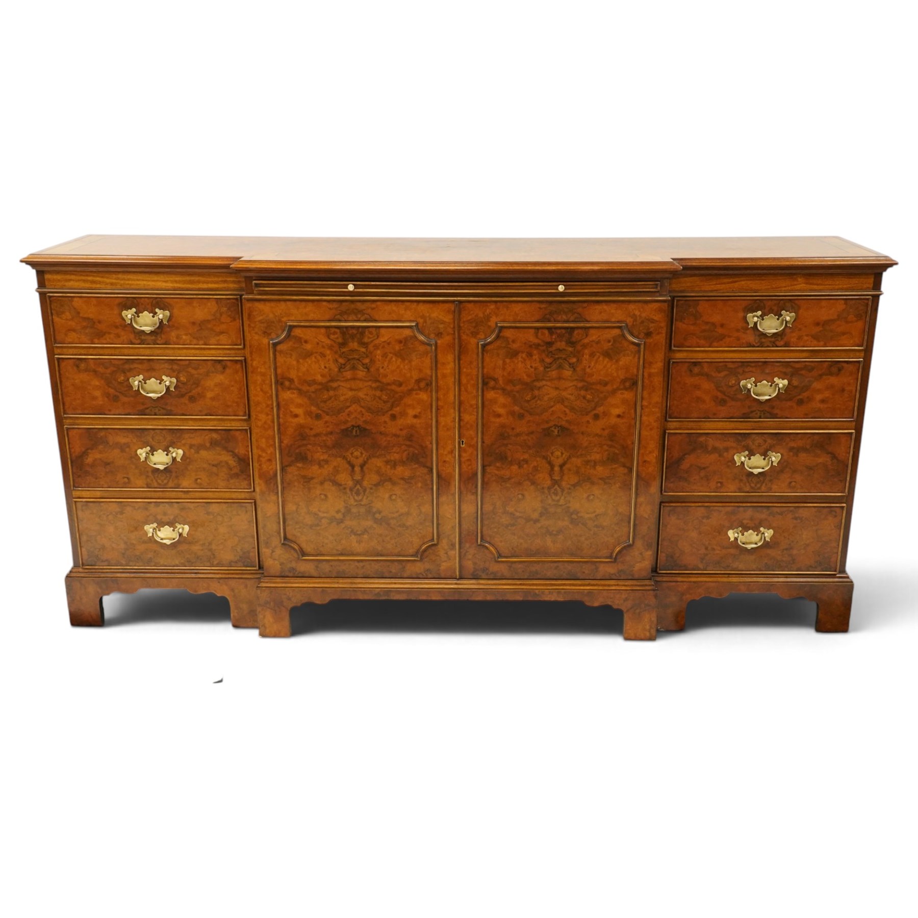 Georgian design figured and burr walnut breakfront sideboard, shaped rectangular top inlaid with crossbanding and stringing, fitted with central brushing slide over cupboard enclosing single adjustable shelf, flanked four graduating cock-beaded drawers to each side, raised on bracket feet