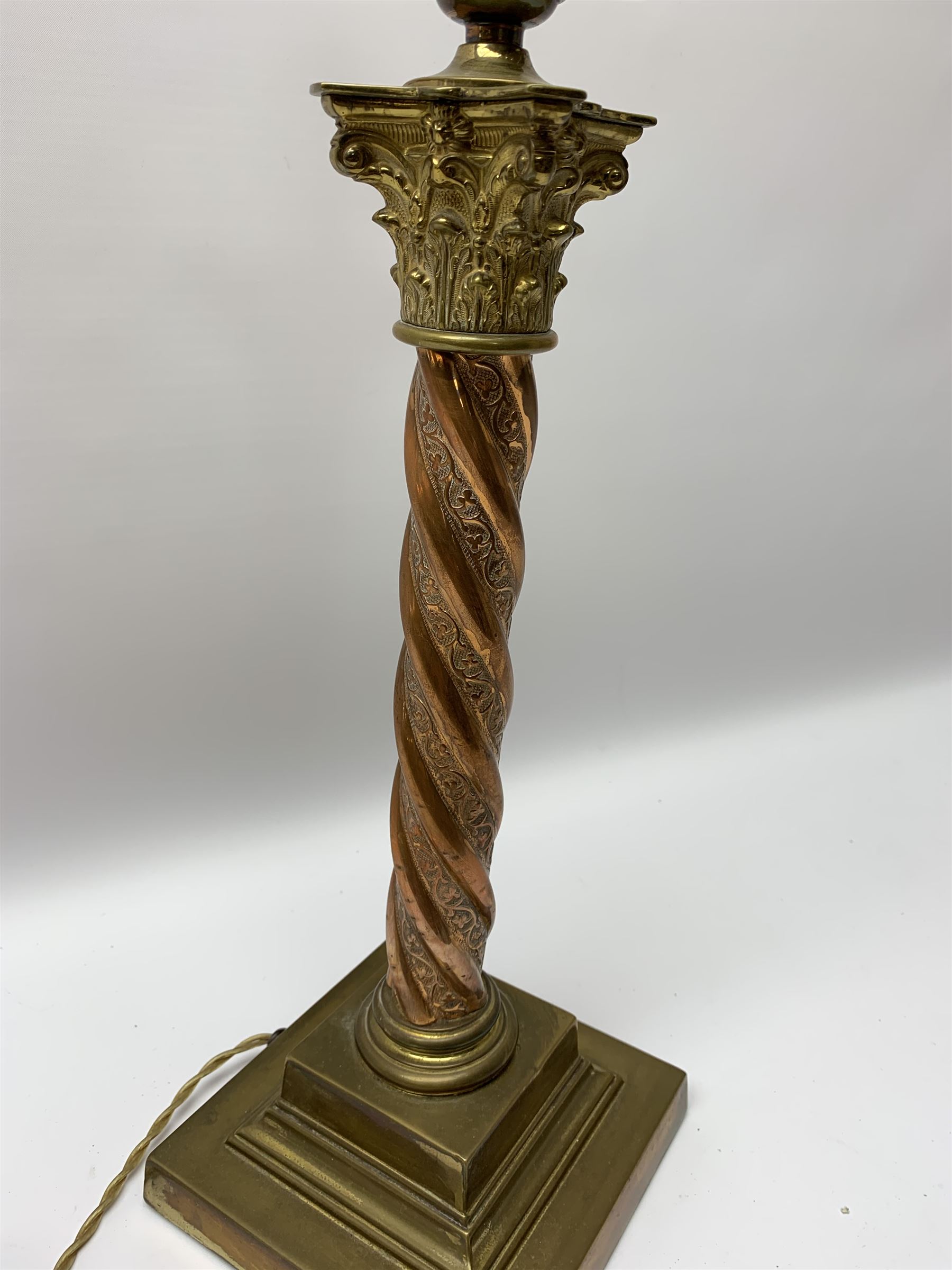 Early 20th century brass and copper Corinthian column table lamp, the square stepped brass base leading to a spiral twist copper column and brass Corinthian capital, H44.5cm 