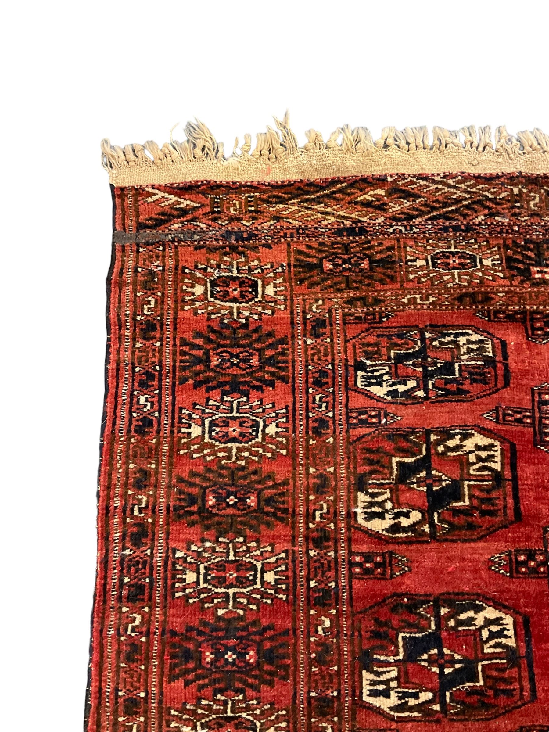Bokhara red ground rug, decorated with two rows of Gul motifs, the border with geometric guard bands decorated with stylised plant motifs