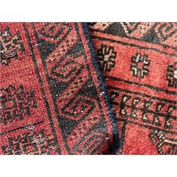 Afghan Bokhara red ground rug, the field decorated with three rows of Gul motifs, within multiple band borders decorated with trailing hook and geometric motifs 