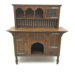 Arts and Crafts period oak sideboard, raised triple shaped arch top fitted with cupboard, rectangular top over three drawers and two cupboards, panelled doors relief carved with foliate urn, turned supports, ivorine label to door interior inscribed 'J. K Thomson... Falkirk', W151cm, H159cm, D53cm