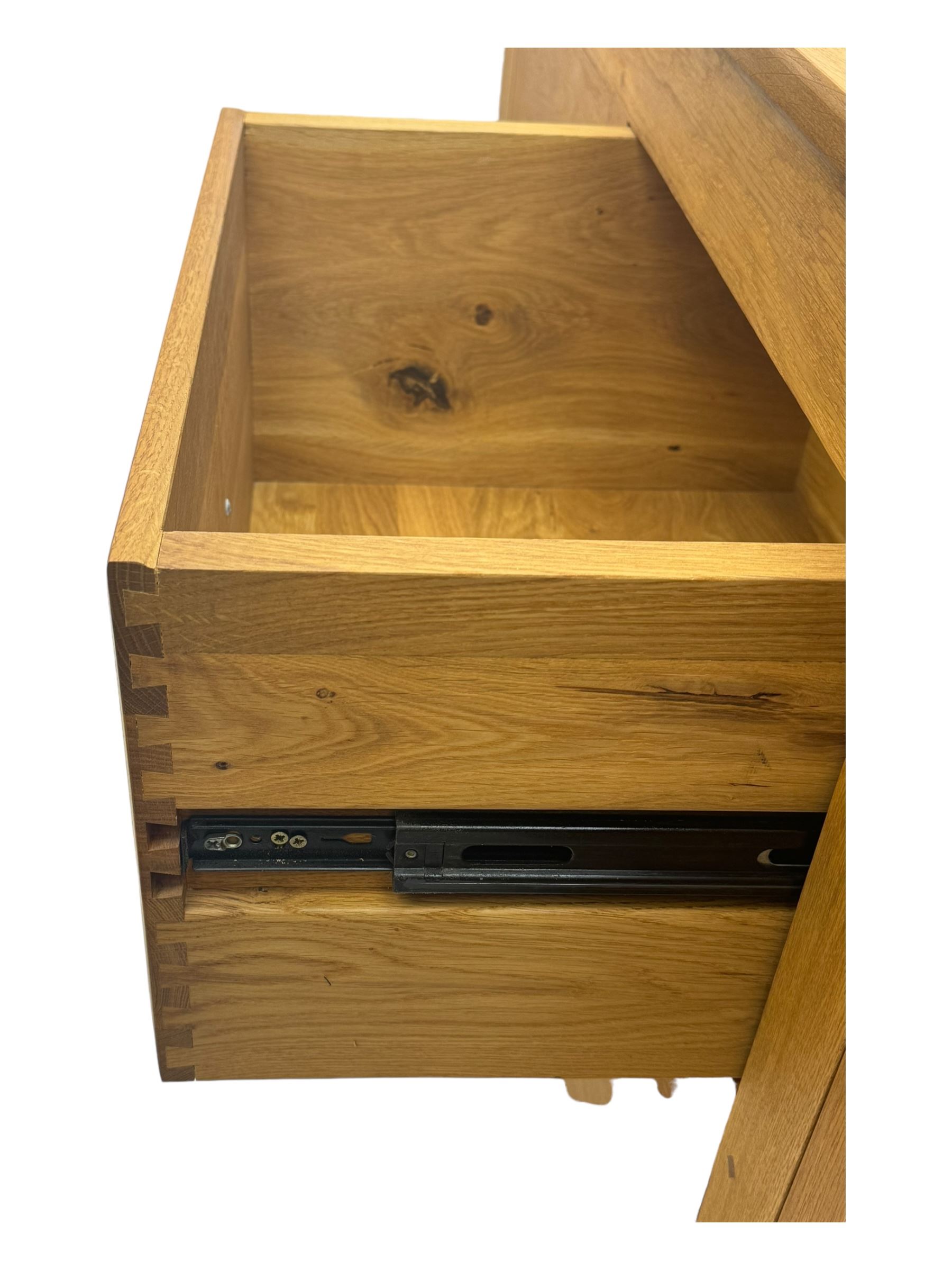 Contemporary light oak sideboard, chamfered rectangular top over two central bevel-edged drawers, flanked by two recessed panelled cupboards enclosing shelving, on square stile supports