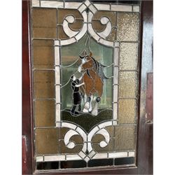 Two early to mid 20th century timber doors, set with lead framed stained glass panels depicting agricultural worker and horse