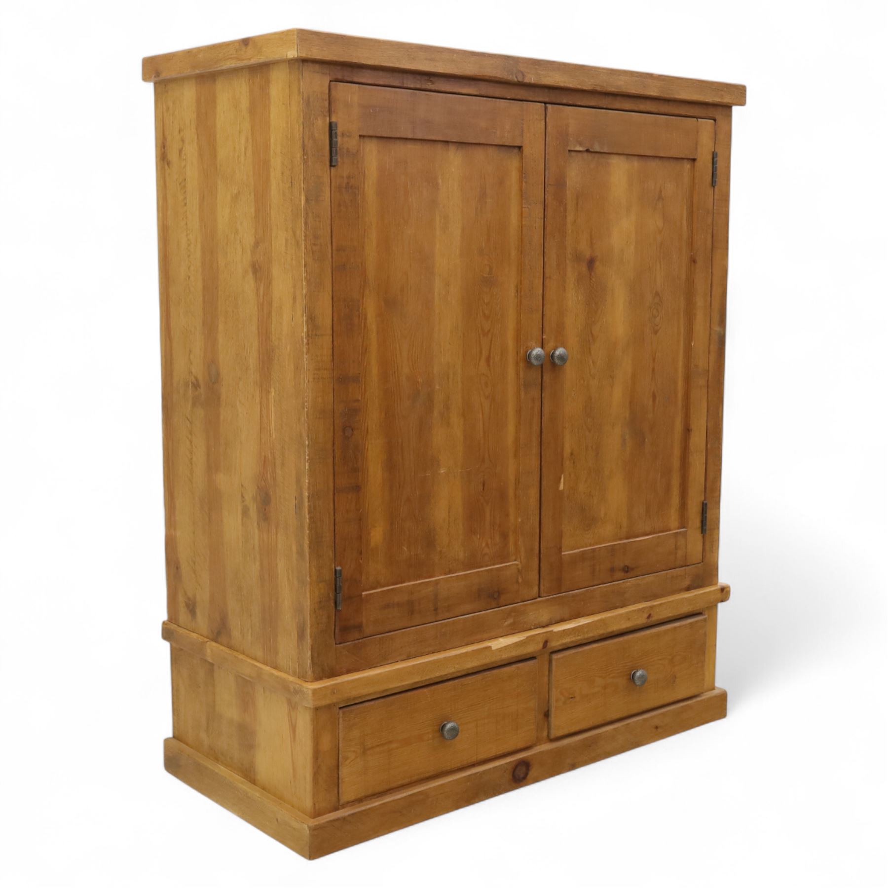 Contemporary pine hanging wardrobe, twin panelled doors enclosing open hanging space with brass rail, two drawers to lower section, on moulded plinth base