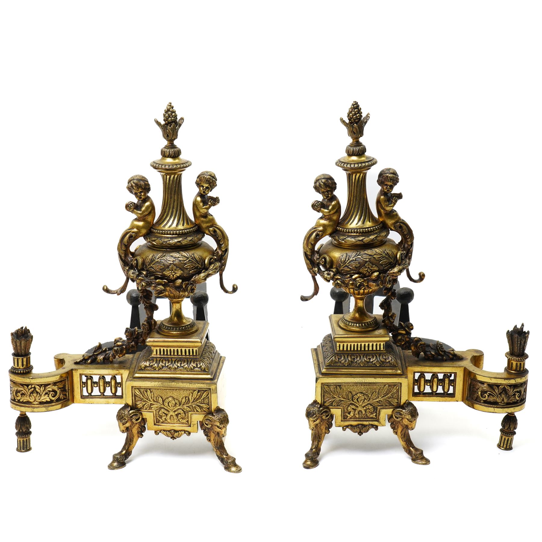 Pair of gilt metal fire dogs, formed as an urn with classical decoration, including putti and floral swags, raised on a square stepped base, the feet formed as rams heads and hoofs, H45cm x W28cm