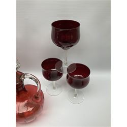 Group of cranberry glass, comprising three ewers with clear glass stoppers and fluted rims, two jugs and a set of six wine glasses