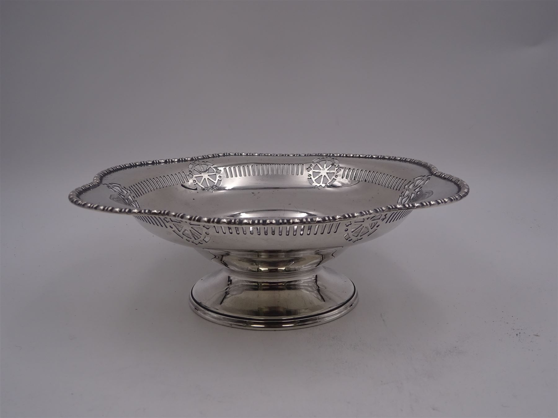 Early 20th century pedestal bowl, of circular form, with lobed bead and dart rim, the sides with pierced wheel, cross and dart decoration, upon spreading circular foot, hallmarked Barker Brothers, Chester 1917