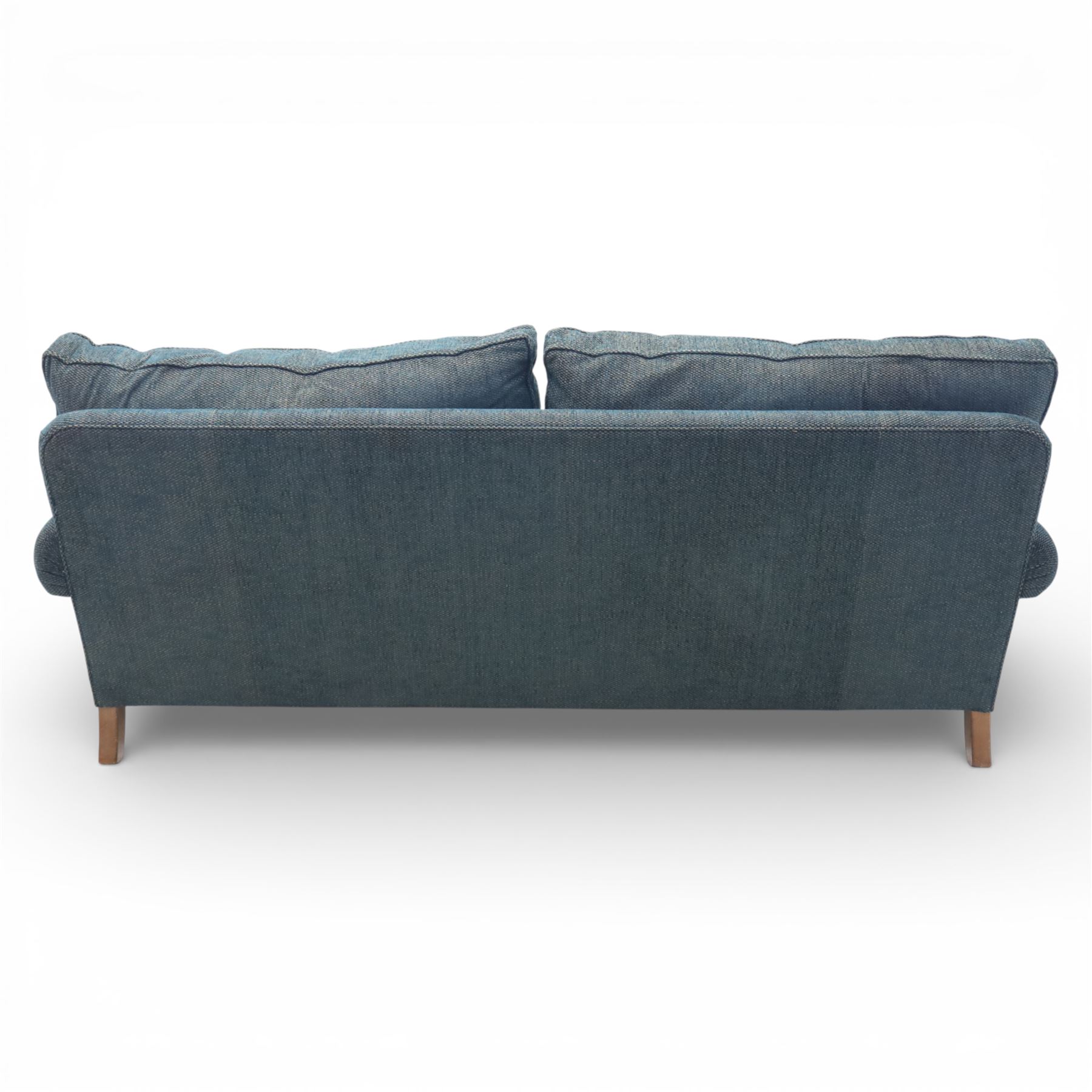 Late 20th century three seat sofa upholstered in green fabric, with gently rounded scroll arms, loose seat and back cushions, raised on turned wooden legs with castors, rear splayed legs