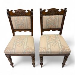 Victorian walnut set of four dining chairs, the shaped and carved top rails with central flowerhead and scroll decoration above upholstered backs and seats in floral woven fabric, brass stud trim, on ring turned front supports