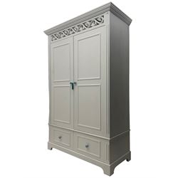 White painted double wardrobe, pierced scrolling foliate frieze over two doors enclosing hanging rail and two shelves, two drawers fitted to base, with blue ceramic handles