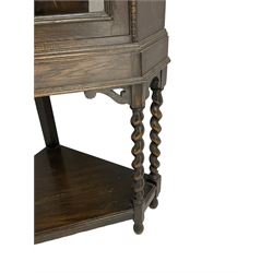 Early 20th century oak corner display cabinet, enclosed by glazed door, on spiral turned supports joined by undertier 
