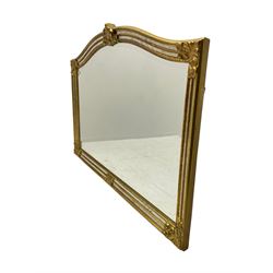 Gilt cushion framed wall mirror, arched top with central stylised fleur-de-lis decoration and cartouche corners