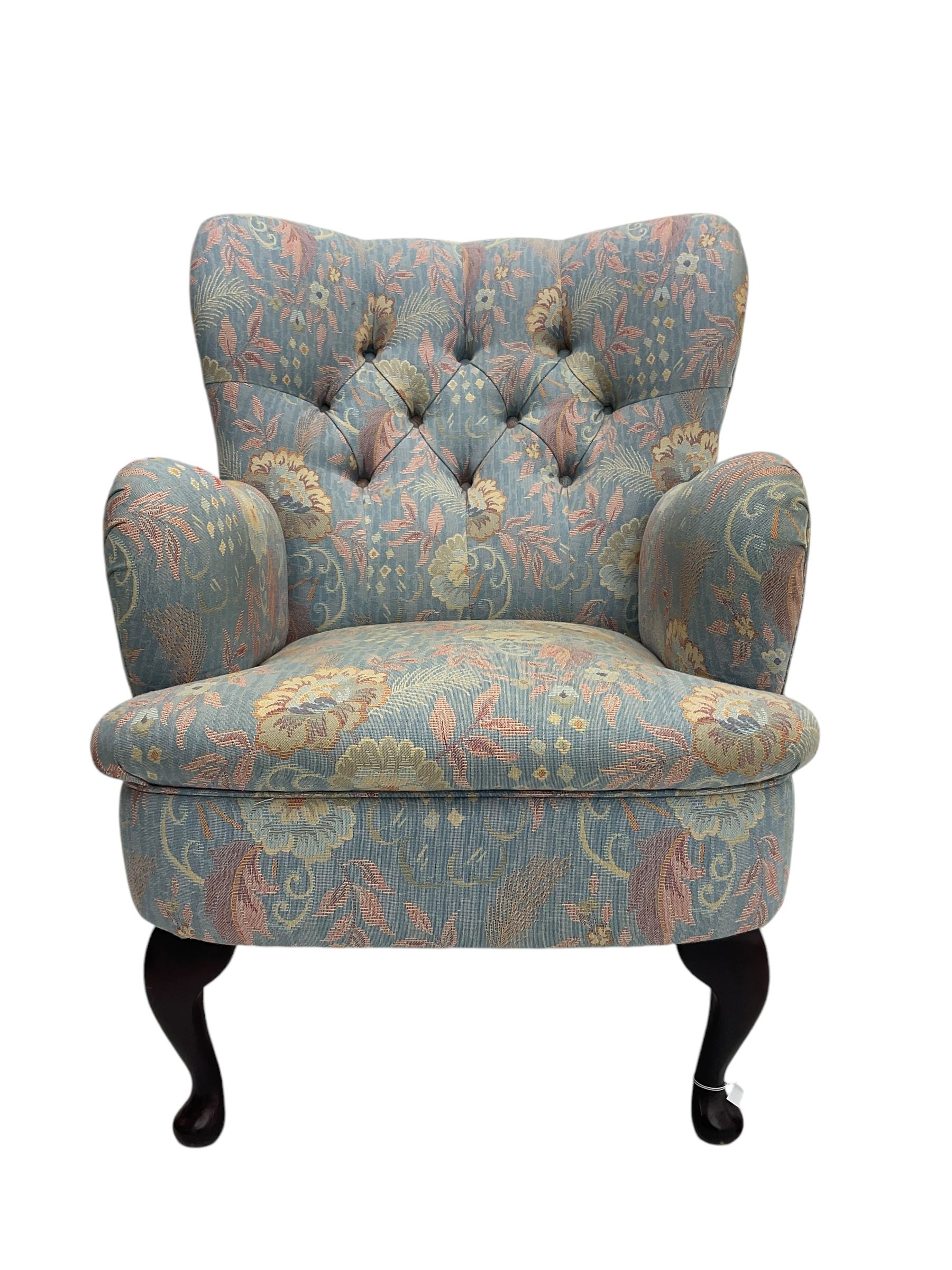 Mid-20th century wingback armchair, upholstered in soft blue floral patterned fabric with button-tufted backrest and curved arms and raised on cabriole supports