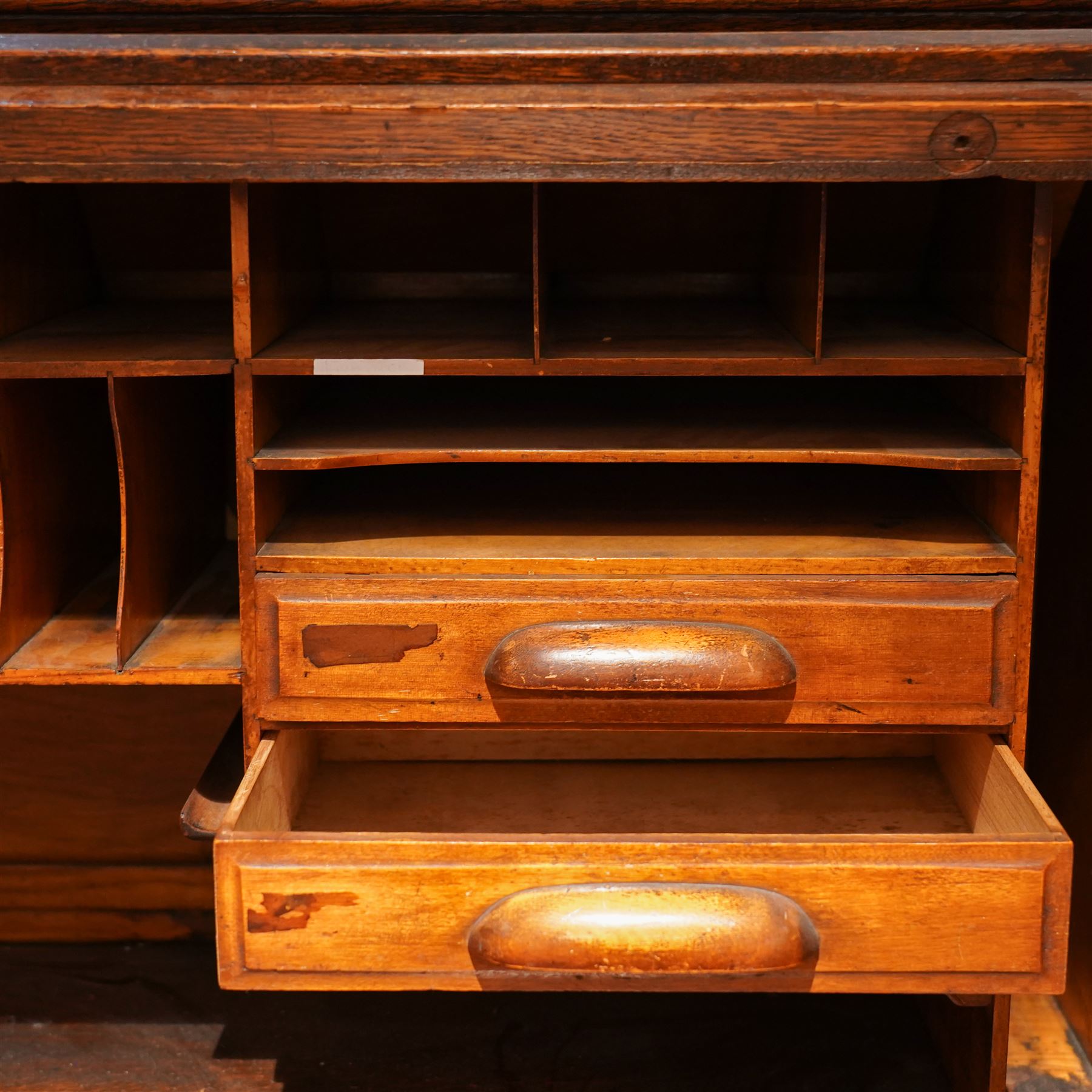 Early 20th century oak twin pedestal roll top desk, tambour roll enclosing small drawers and pigeon holes, fitted with seven drawers, on plinth base 