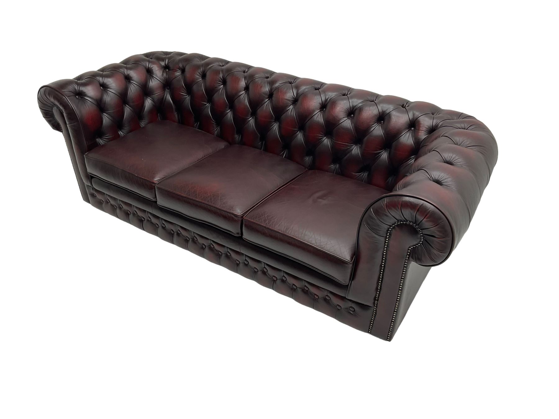 Thomas Lloyd - three seat Chesterfield sofa, upholstered in buttoned oxblood leather, on castors 
