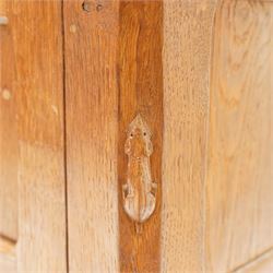 Mouseman - early-to-mid-20th century adzed and panelled dark oak bedside cupboard, raised back over rectangular canted top, fitted with single panelled cupboard door with chamfered rails and wrought iron fittings, enclosing two adjustable shelves, raised on canted square feet, carved with mouse signature, by the workshop of Robert Thompson of Kilburn
