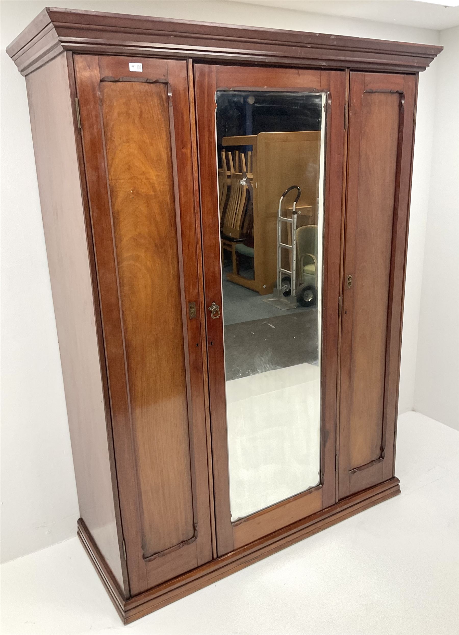 Victorian mahogany triple wardrobe, central mirrored door enclosing linen slides and two short and two long drawers flanked by two cupboards, plinth base