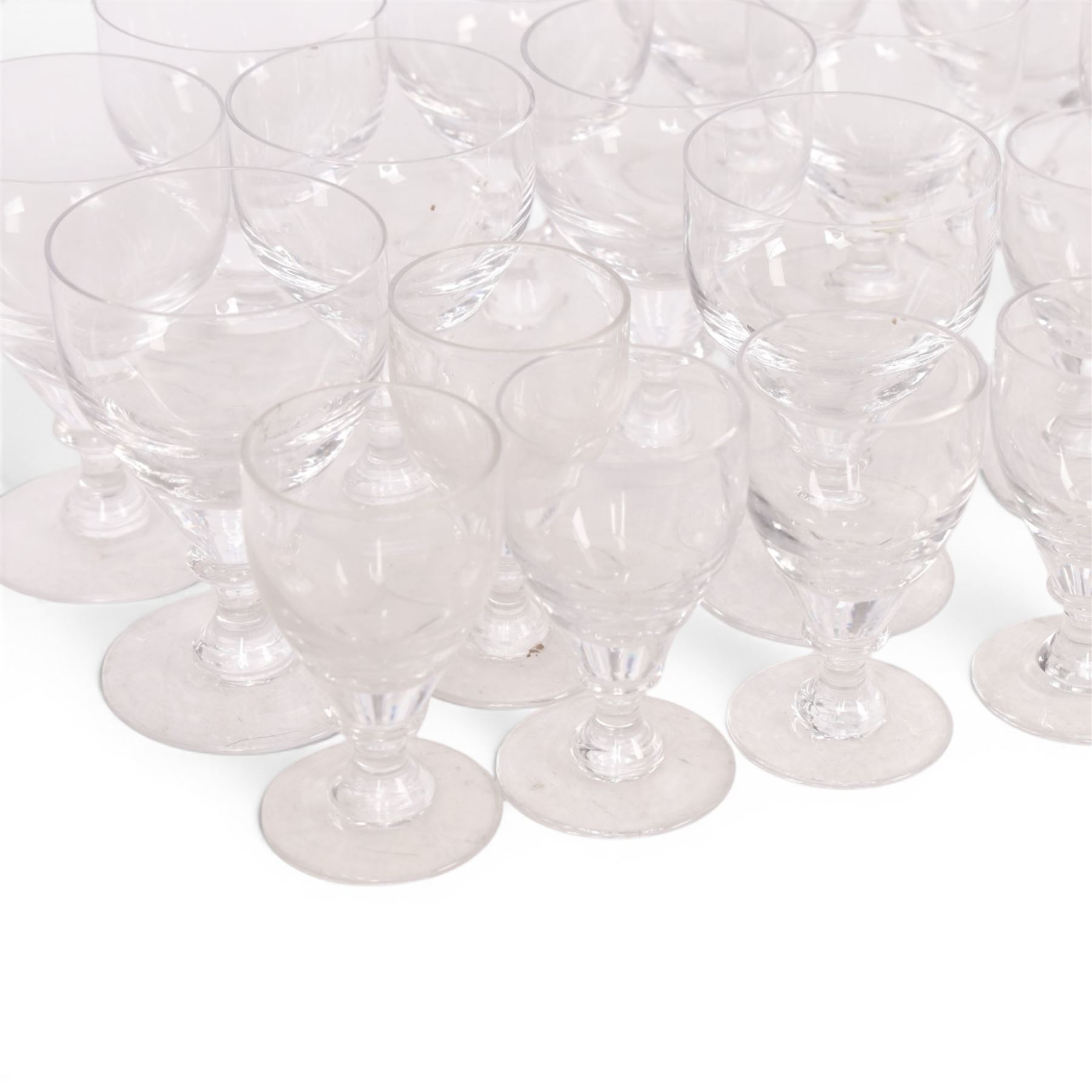 Georgian shaped drinking glasses, comprising eleven larger, H12.5cm, and eight smaller, H10.5cm, each with ovoid bowl upon knopped stem and circular foot