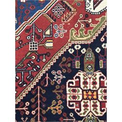 Fine Persian Qashqai crimson and navy ground runner, three large medallions filled with geometric and floral designs, the field with angular vines and stylised floral decoration, wide ivory border decorated with repeating floral and angular motifs