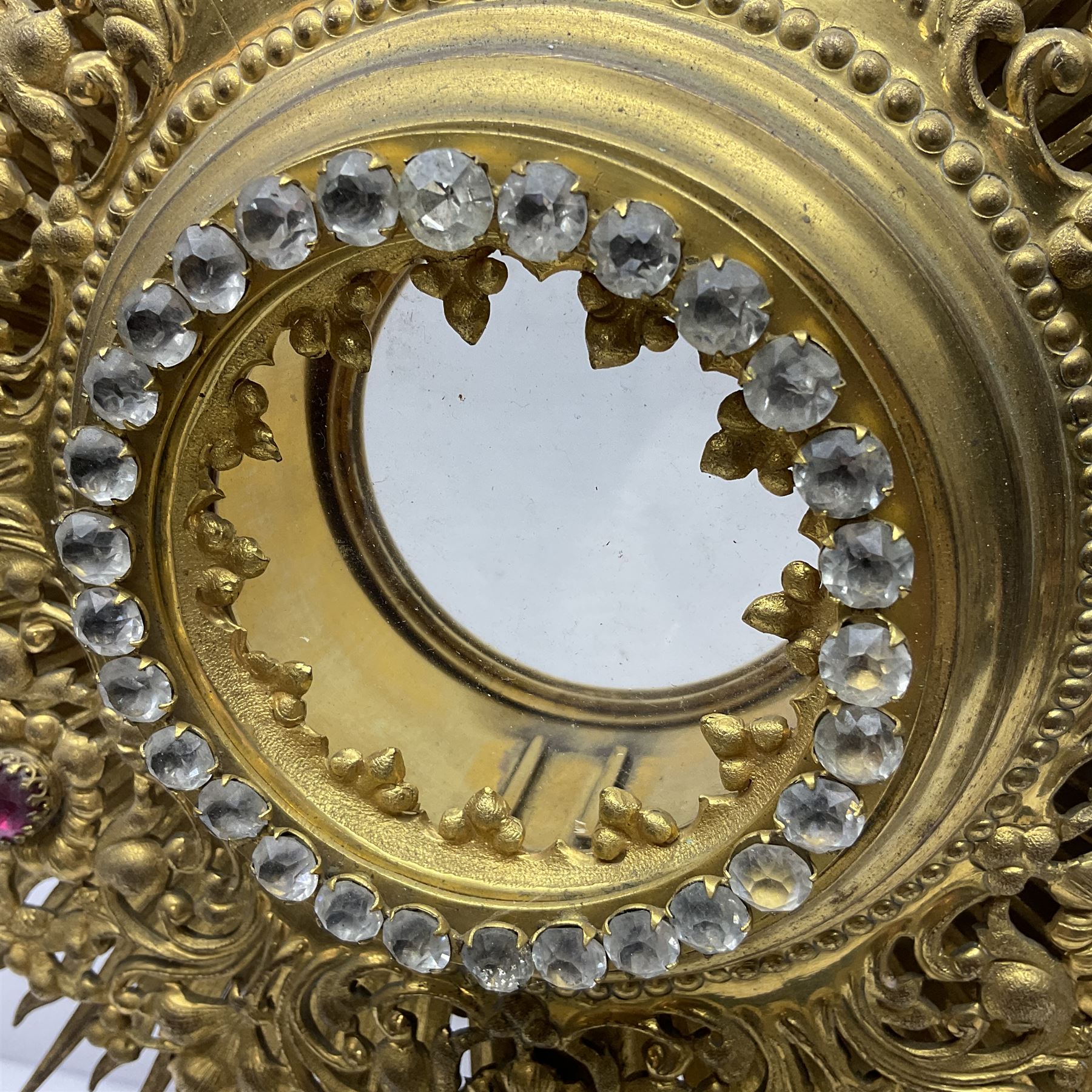 20th century gilt metal monstrance, in the Gothic revival style, with glazed aperture to centre surrounded with clear paste stones, in a pierced floral and scroll border set with coloured paste stones, within a sunburst surround, on a paste set knopped stem and similar foliate foot, H59.3cm