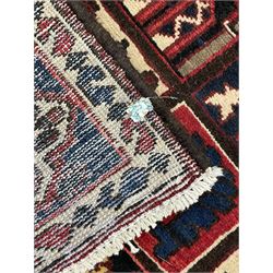 Persian red and blue ground rug, overall geometric and stylised design, the field with repeating squares each decorated with stylised motifs, three band border, the main band decorated with stylised flower heads