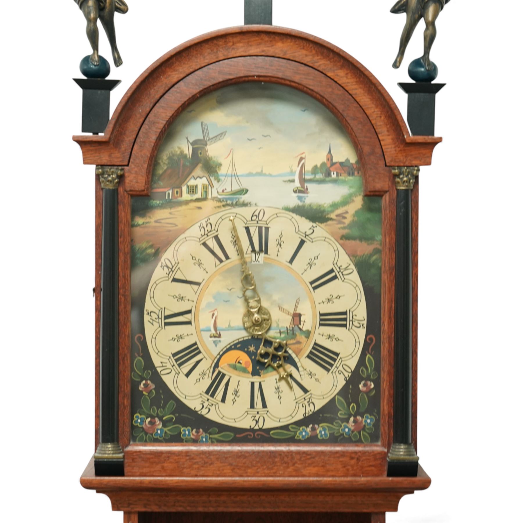 Dutch-mid 20th century Warmink WUBA wall clock, with a full length backboard and break arch hood with ebonised pilasters and three cast figures representing two trumpeting angels and Atlas to the pediment, with a fully painted break arch dial with a working axe moon dial and calendar aperture, chapter with Dutch minute arcading, Roman numerals and five minute Arabic's, three train chain driven countwheel striking movement with alarm and hours sounding on a bell. With three brass weights, brass chains and pendulum.