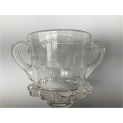 Early 20th century commemorative twin handled pedestal cup, the bucket shaped bowl engraved with flowers of the Union, and inscribed 'In Commemoration of the Durbar Delhi December 12th 1911', the panelled stem containing a silver 3d coin, upon a shaped foot, H20.5cm