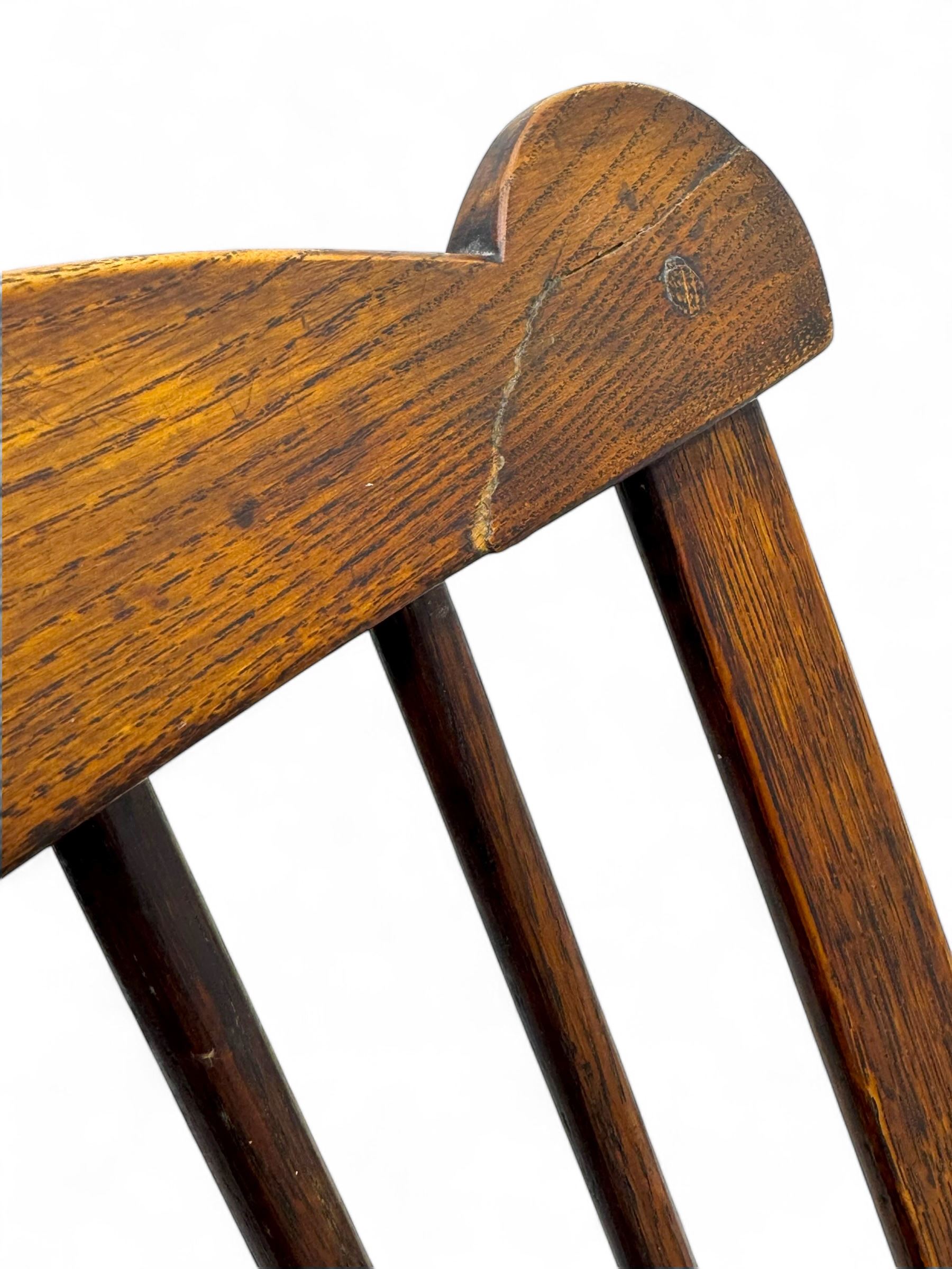 Early-to-mid 19th century elm and ash high-back Windsor armchair, central vase-shaped splat flanked by slender vertical spindles, outward-curving arms, shaped and dished saddle seat, raised on turned and splayed supports united by H-stretcher