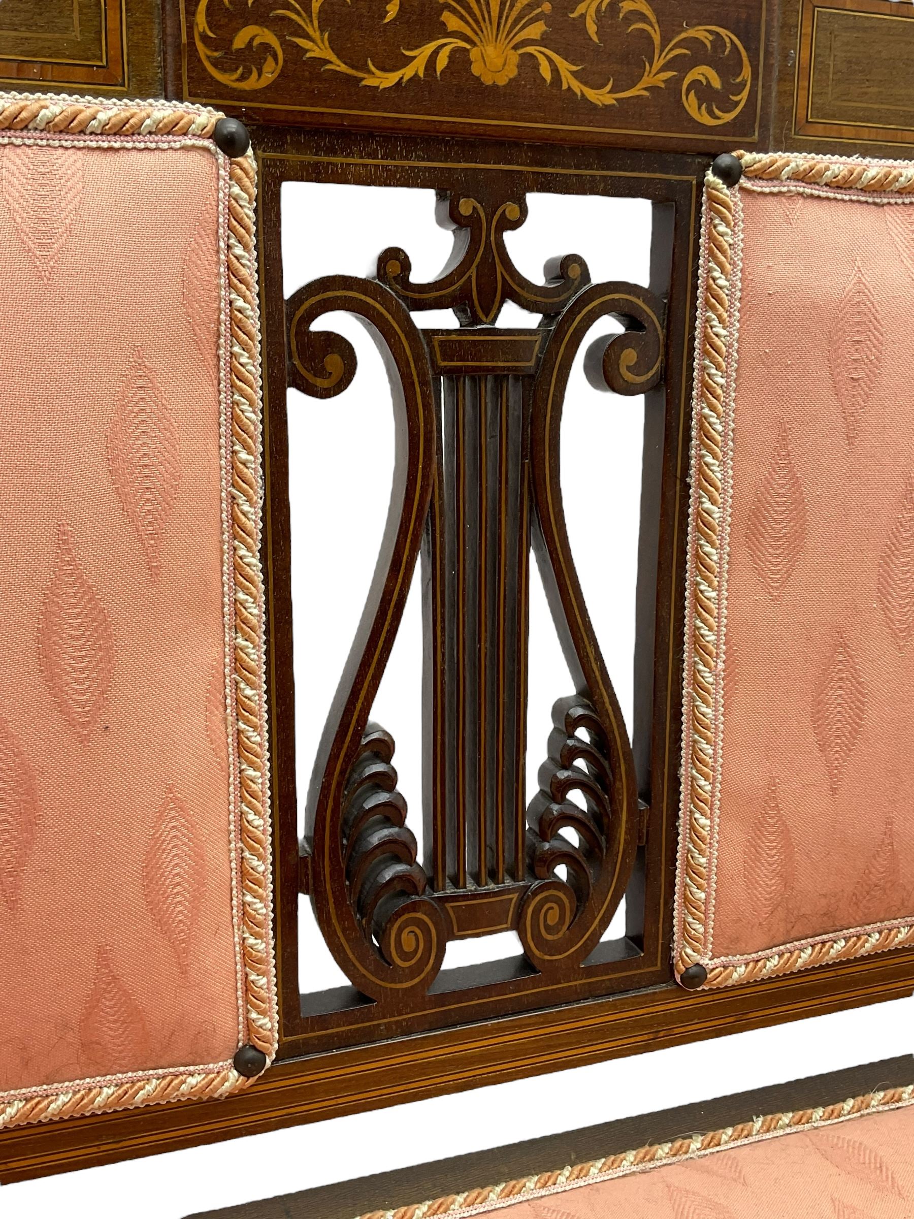 Edwardian inlaid mahogany two-seat settee or hall bench, the cresting rail inlaid with satinwood banding and boxwood stringing, central panel inlaid with scrolled leafy branches over pierced and carved lyre back, upholstered in peach fabric with repeating pattern, scrolled down sweeping arms, on square tapering supports with spade feet 