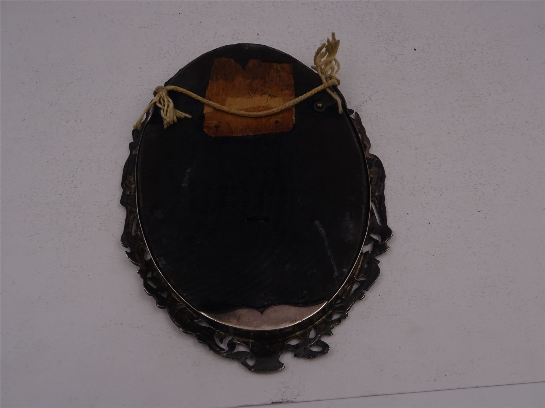 Continental silver miniature dressing table/wall mirror, of oval form with bevelled mirror plate, surrounded by a bead and dart rim, with pierced scrolling floral border with a standing cavalier to either side and the bust of a cavalier to the base, H17.7cm