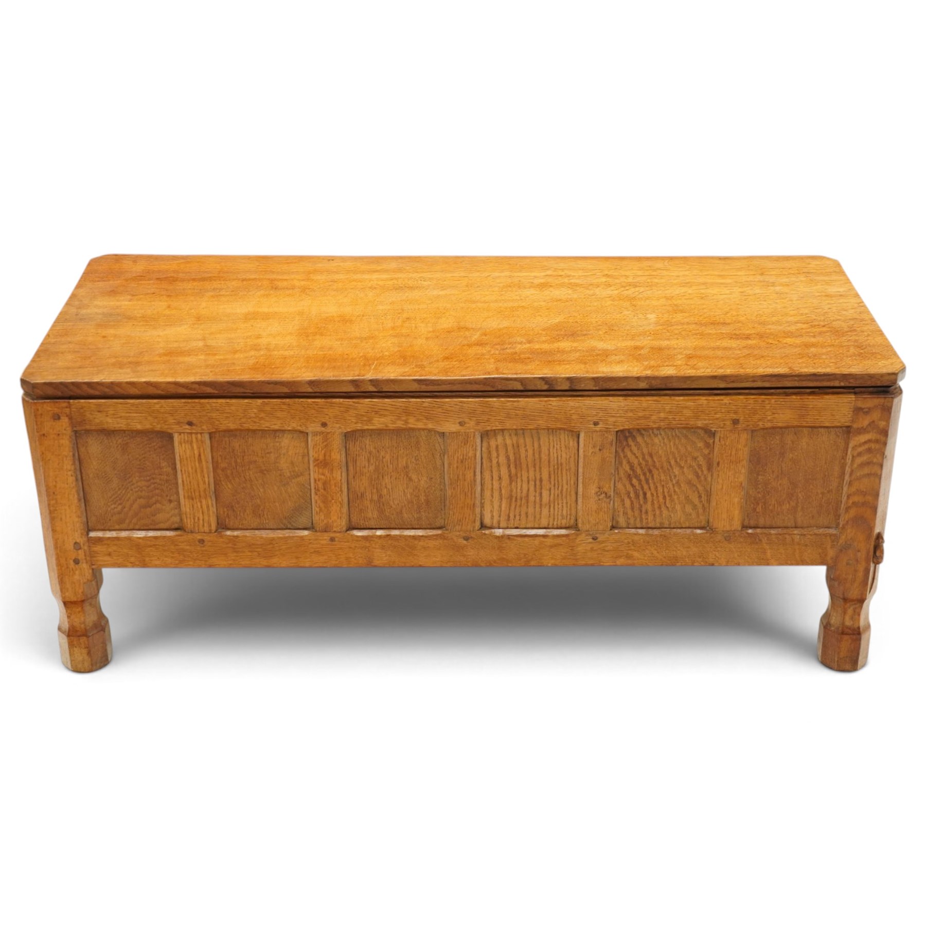 Mouseman - 1950s adzed oak blanket chest of unusual proportions, the rectangular hinged top with canted corners, over a sextuple panelled front, raised on turned octagonal feet, carved with mouse signature, by the workshop of Robert Thompson of Kilburn