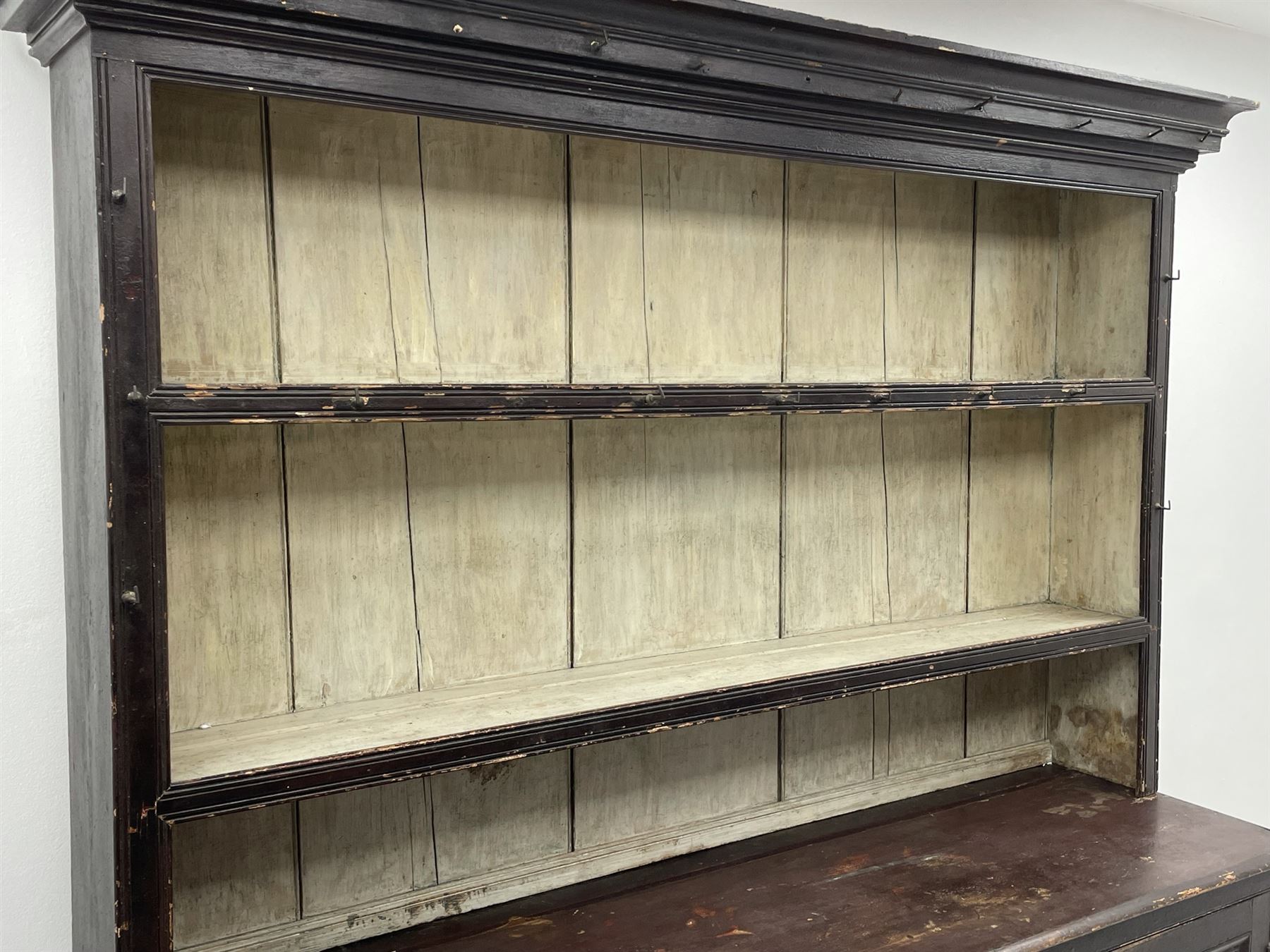 Early 19th century scumbled pine dresser, the projecting cornice over two heights plate rack with moulded frame, the base with reeded canted corners fitted with three drawers and two panelled cupboards, panelled sides, moulded skirt base